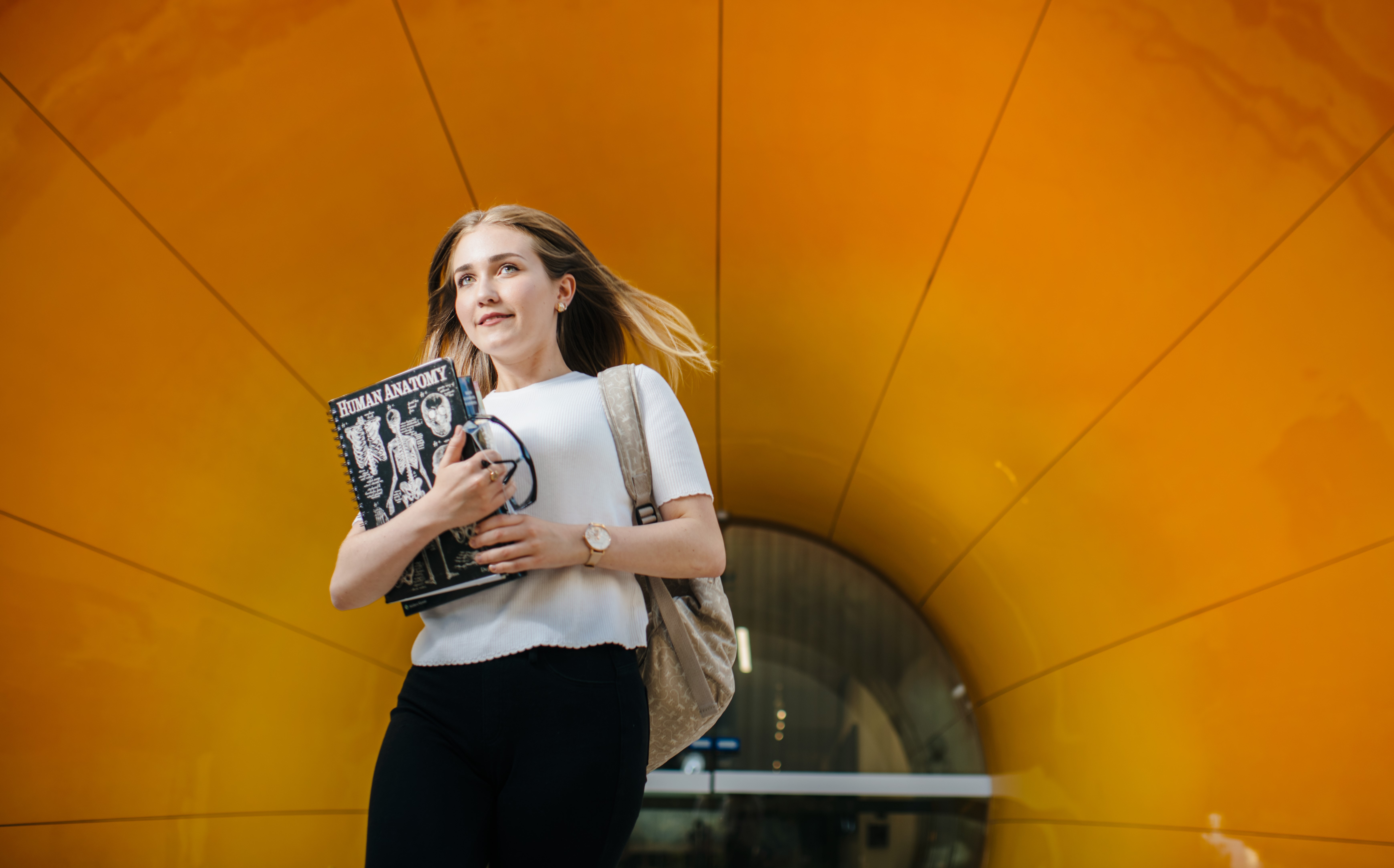 person holding book in front of orange tunnel