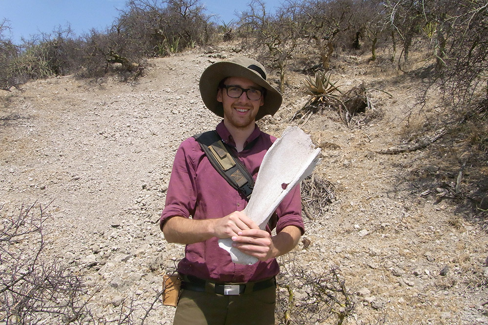 Tim with large fossil bone of megafauna discovered at Olduvai Gorge 2014_low res.jpg