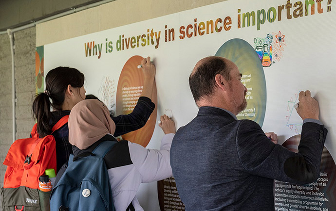 Students and staff draw on a poster titled 