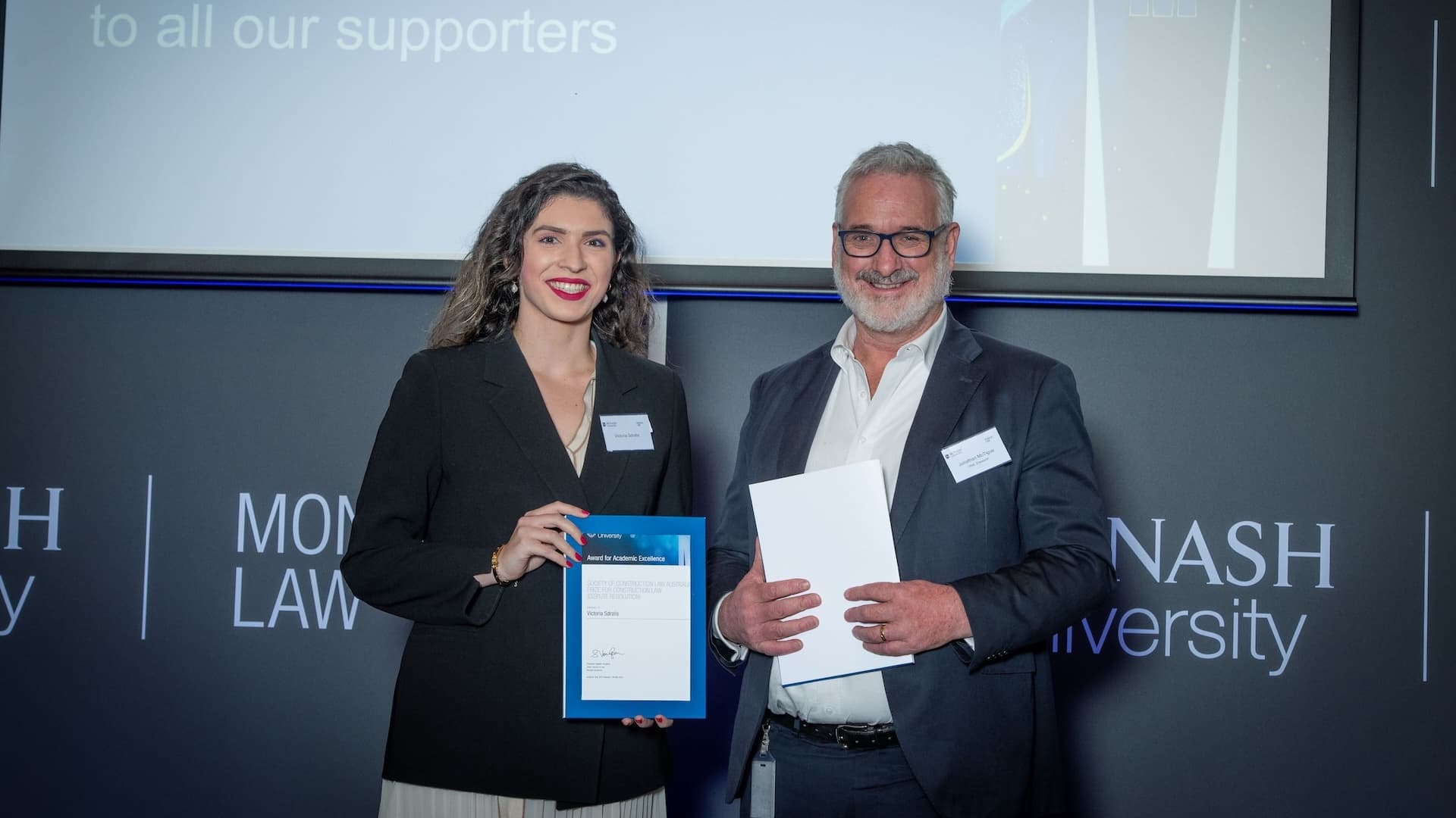 Victoria Sdralis accepts her prize from Jonathan McTigue of the Society of Construction Law Australia.