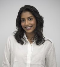 A headshot photo of a person with long dark brown hair wearing a white shirt and smiling at the camera.