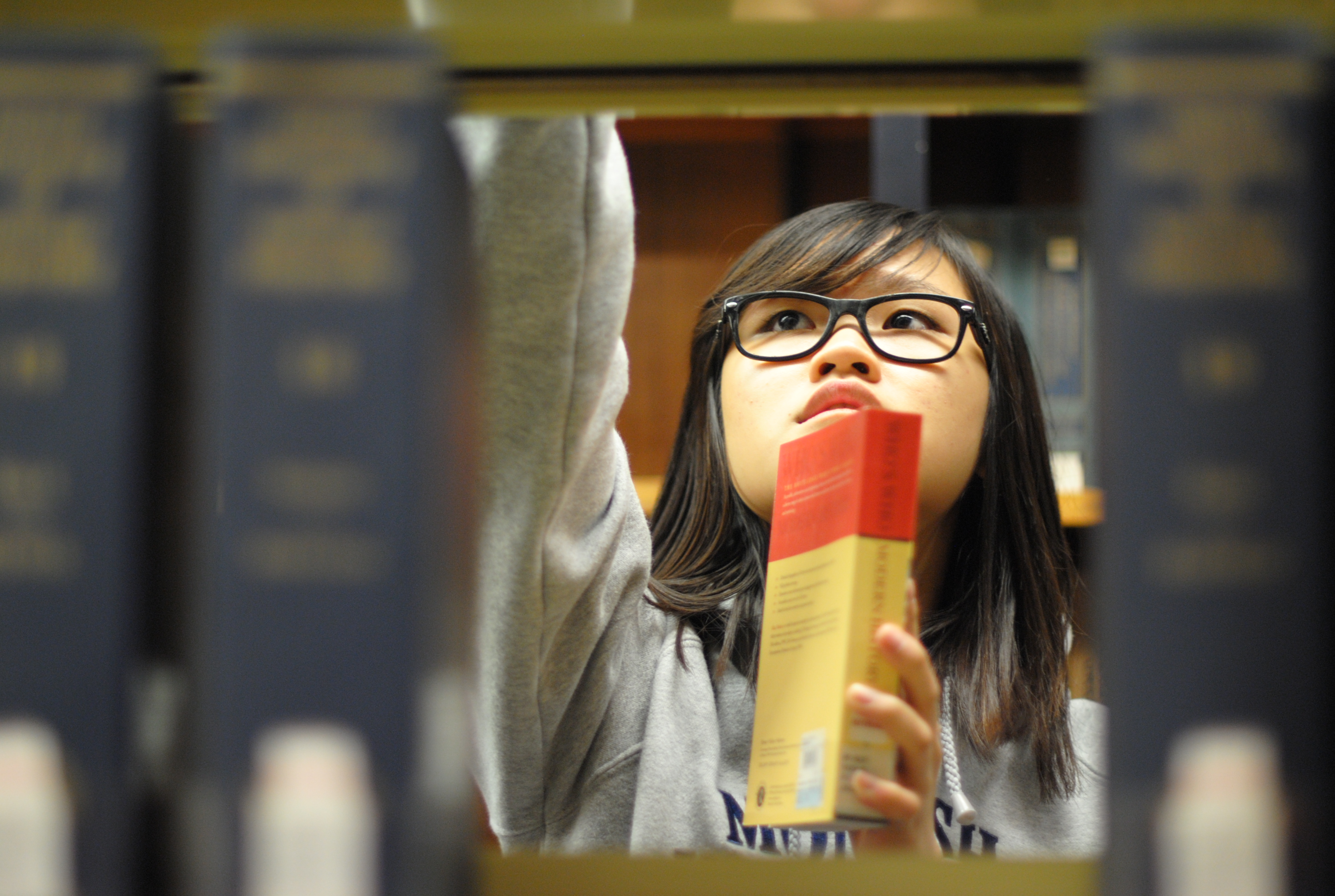 person reaching for book in library