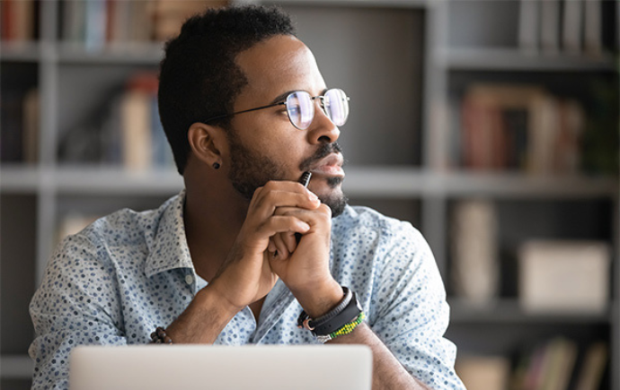 Man sitting in front of a laptop contemplating