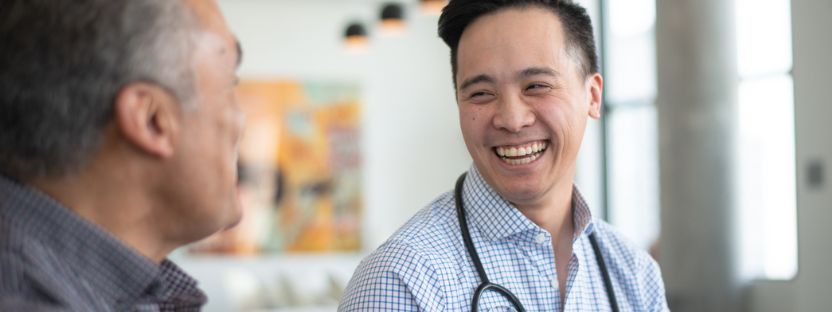 young male doctor smiling with patient 832x312