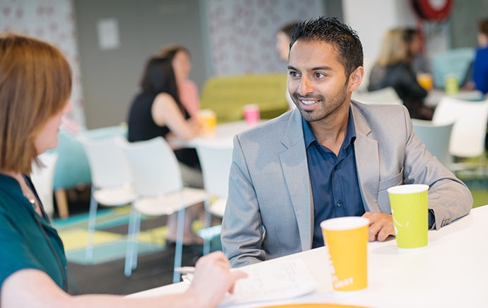 Two staff members talking over coffee