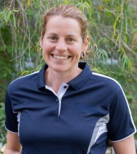 A headshot of Susan Brooks standing outside, wearing a navi t-shirt smiling at the camera.