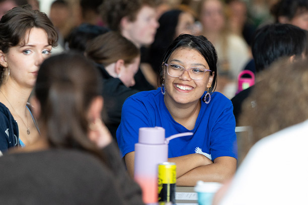 Student smiling at a group of classmates in a classroom.