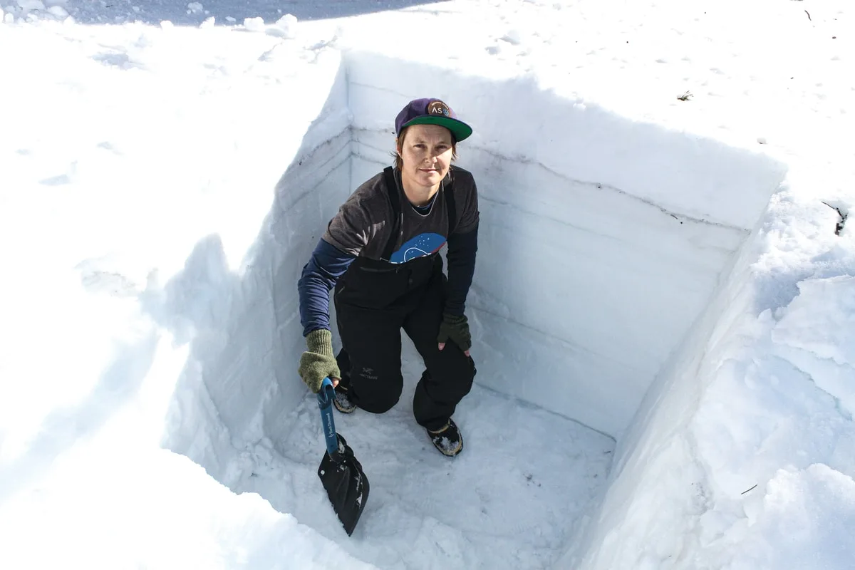 Kat Bormann standing in hole shovelled into snowpack