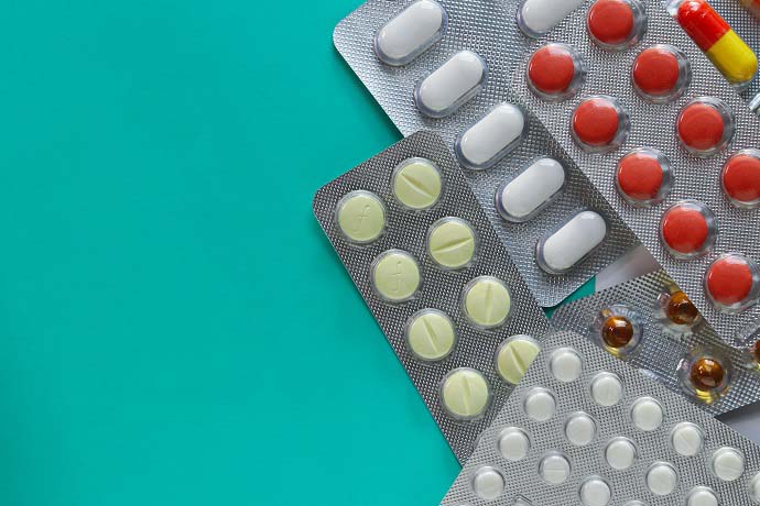 blister packs of different medication against a teal background