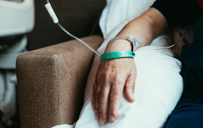 Person sitting on a chair or couch with a drip on their wrist.
