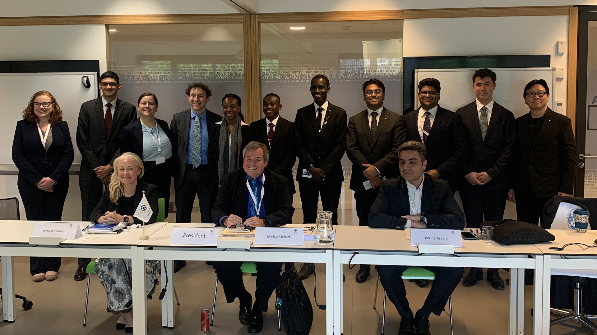 Image: L to R (seated) are panel judges, Kirsten Calhorn, Professor Michael Scharf, Professor Pouria Askary. Standing are the mooting teams including Strathmore University and Monash University