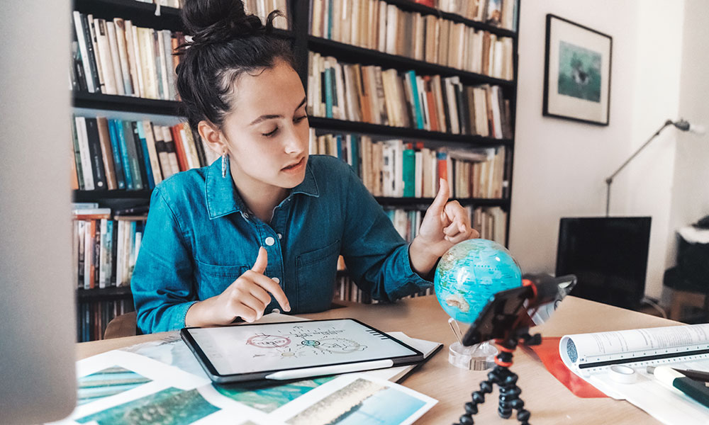 girl studying at home using an ipad and a phone
