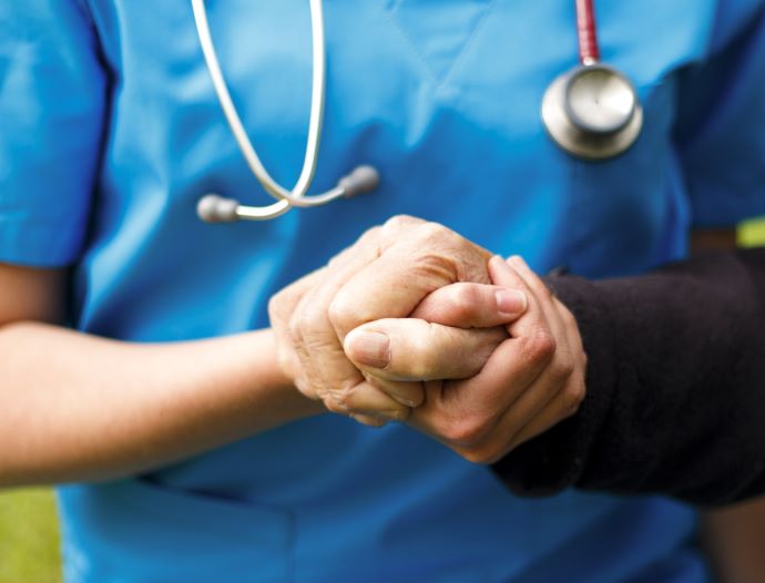 aged care nurse holding patient hand