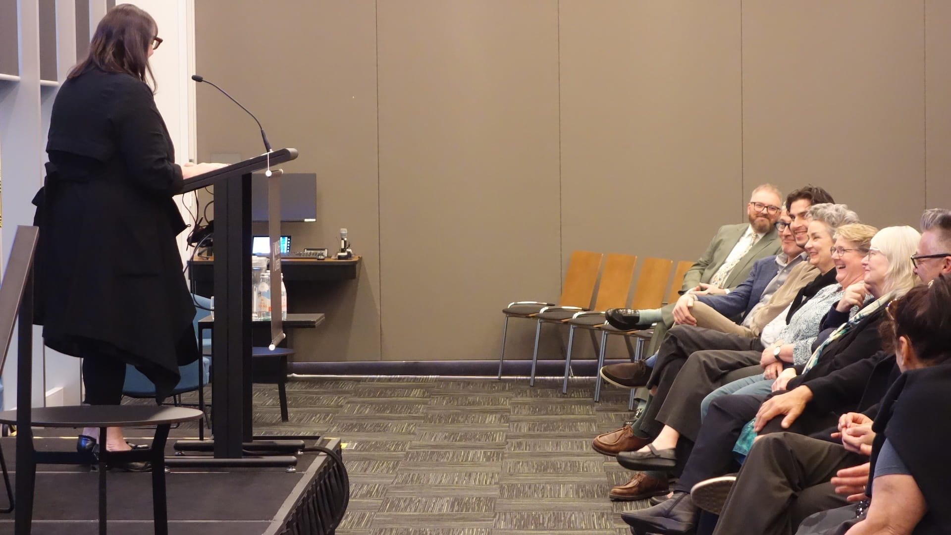 Professor Melissa Castan standing at a lectern in front of an audience