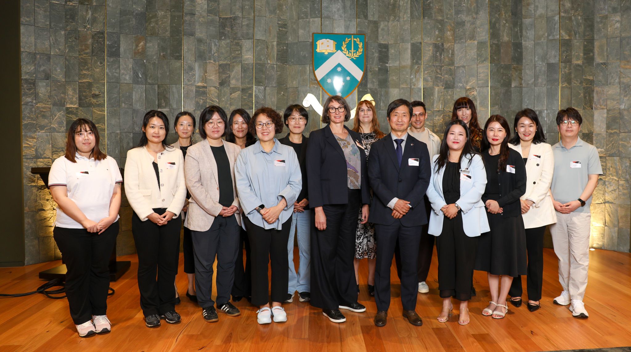a group of people gathered in front of the Monash University logo