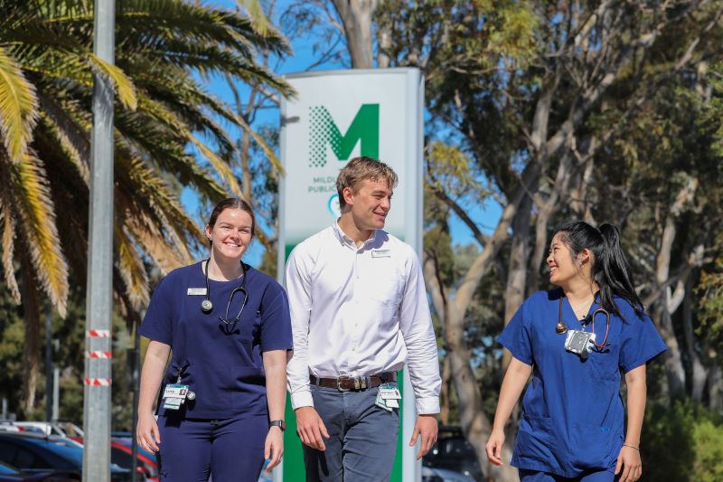 Three Monash medical students in Mildura, walking past Mildura Base Public Hospital sign