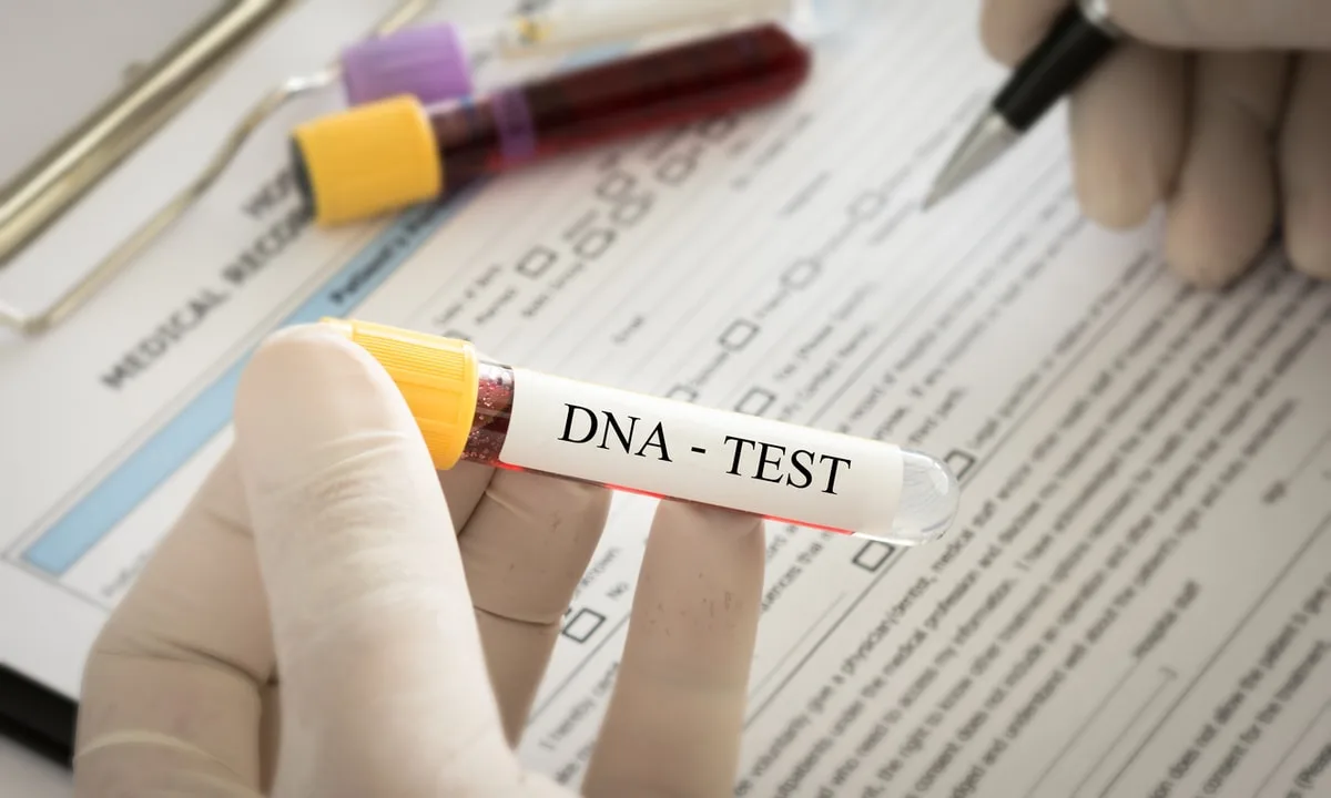 Hand holding a vial of blood labelled DNA test