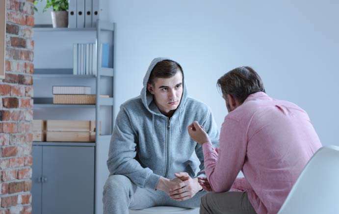 A psychology specialist explaining an action plan for recovery to a troubled teen