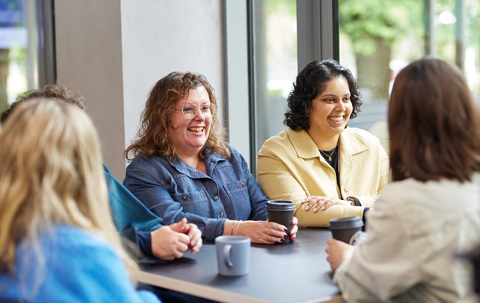 Dr Betty Exintaris and Dr Nilushi Karunaratne talking with a group of colleagues in a cafe