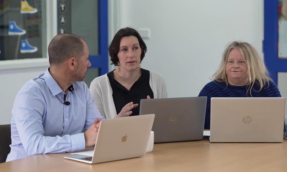 three teachers from St Jude's St Jude’s Primary School in Victoria Australia are talking at a desk