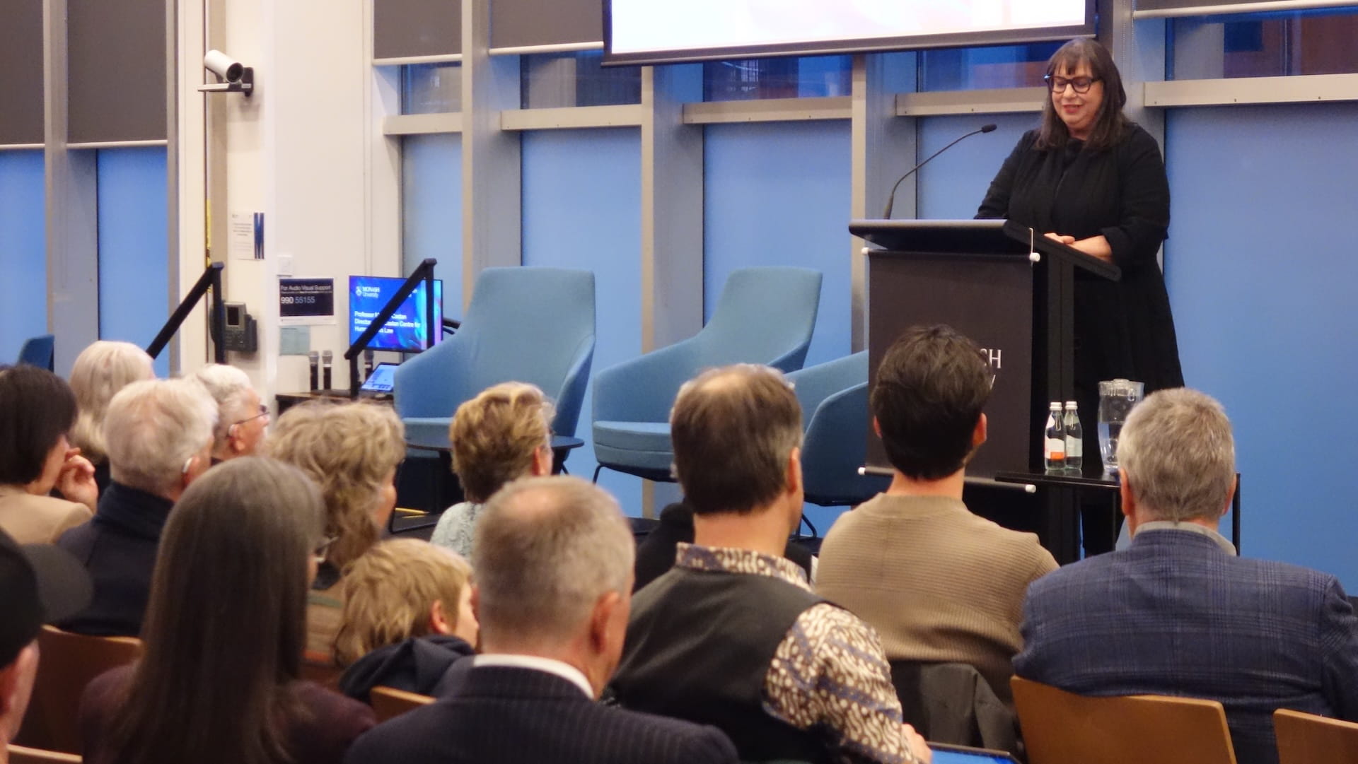 Professor Melissa Castan standing at a lectern in front of an audience