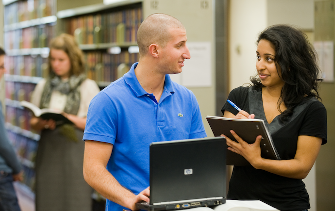 Two people talking in library in front of printer