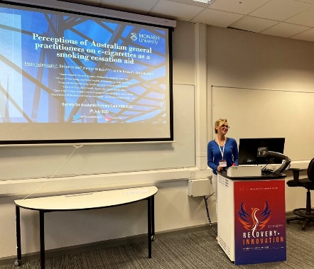 Melis standing at lectern giving conference presentation.