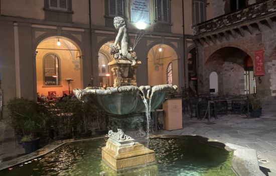 An Italian stone fountain with a statue of a child on top