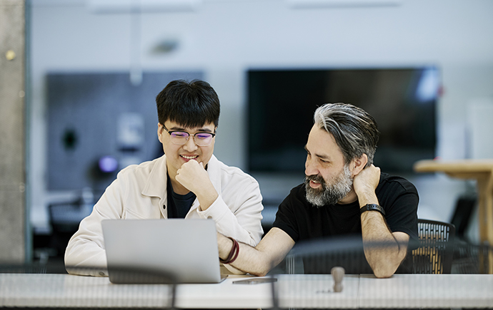 Academic chatting with student at desk