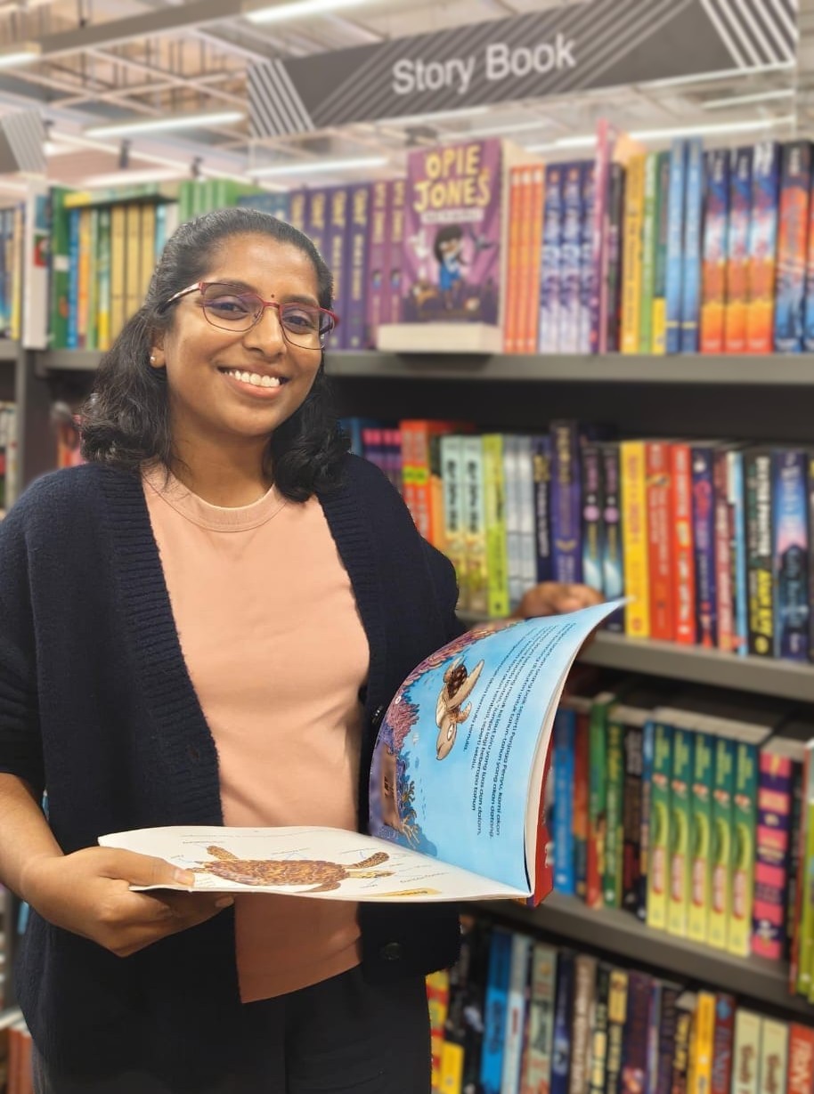 Dr Geetha Maniam holding a children's book