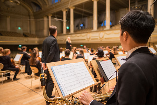 Orchestra musicians perform in a concert hall.