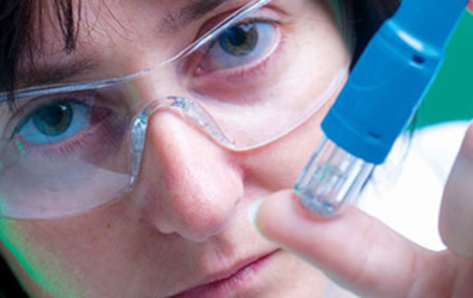 Scientist holds up an oxytocin inhaler looking at it
