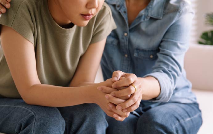 Middle aged person holding the hands of a young woman