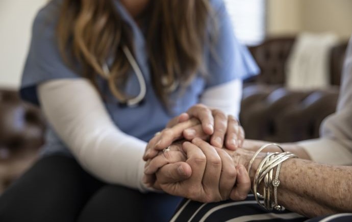Carer holding aged care resident's hand