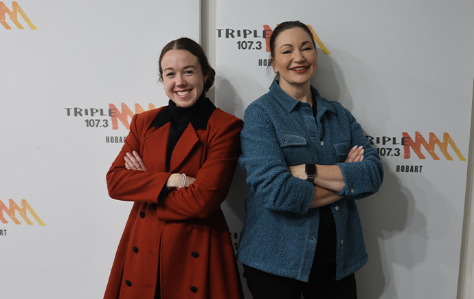 Amelia and Kaz standing next to each other in front of a Triple M media wall