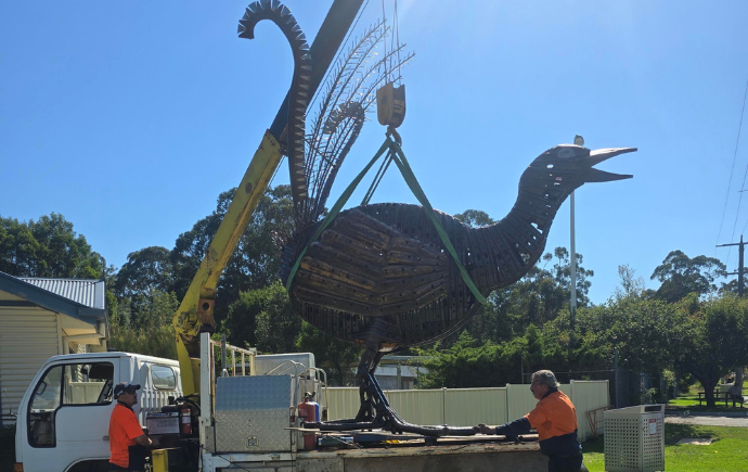 Photo of lyrebird sculpture being moved from the back of a truck by two men