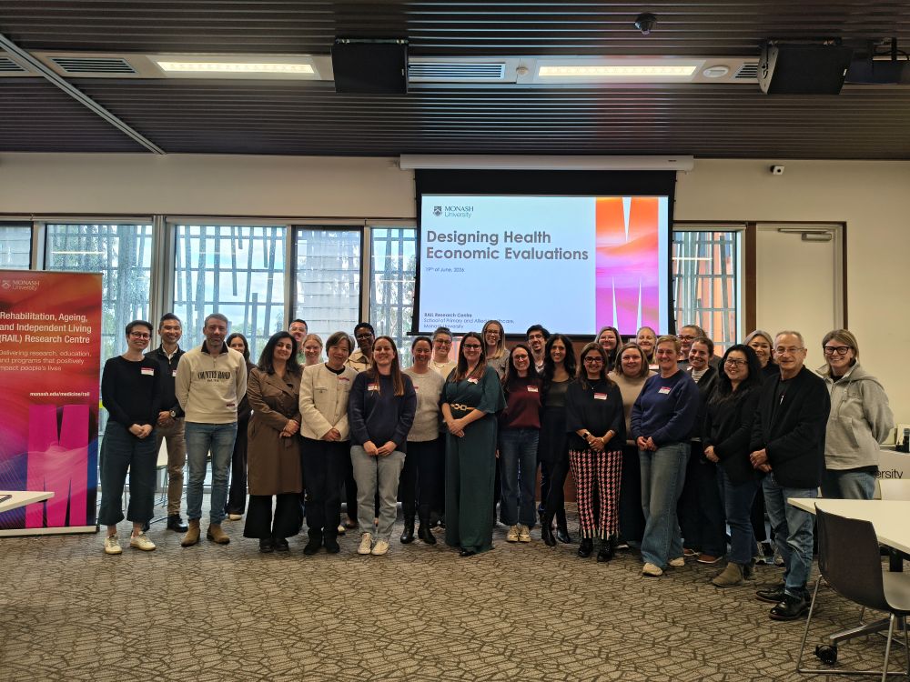 A group of people standing in a classroom next to the RAIL Research Centre banner, smiling at the camera.