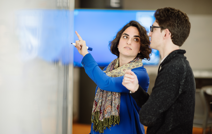Monash staff explaining concept to student via whiteboard