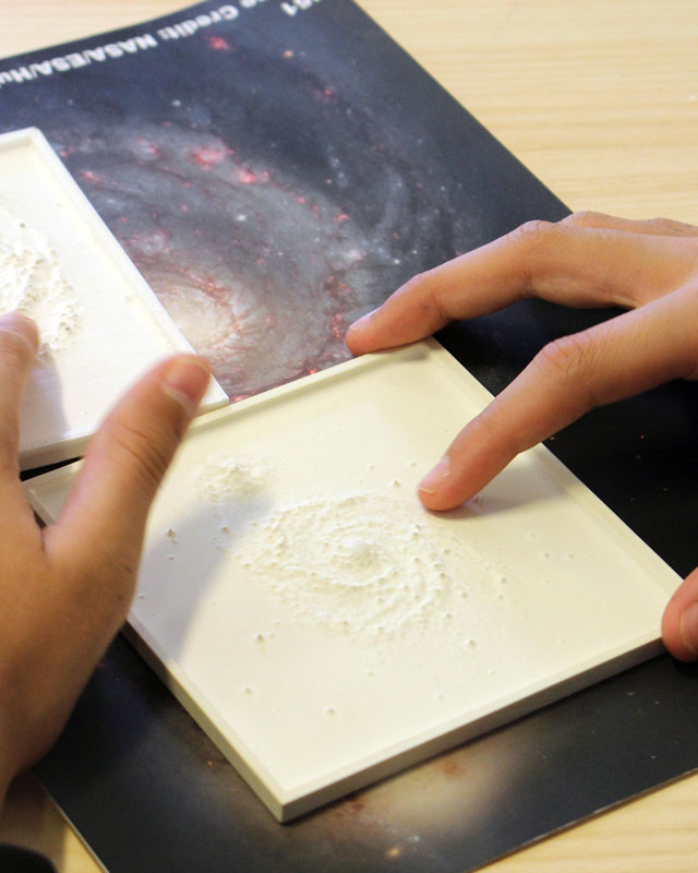 Student touching physical model of Milkyway galaxy