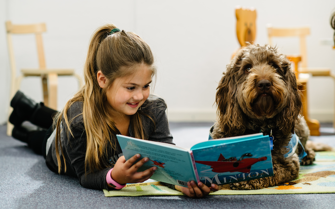 Child reading book to dog at Monash childcare centre