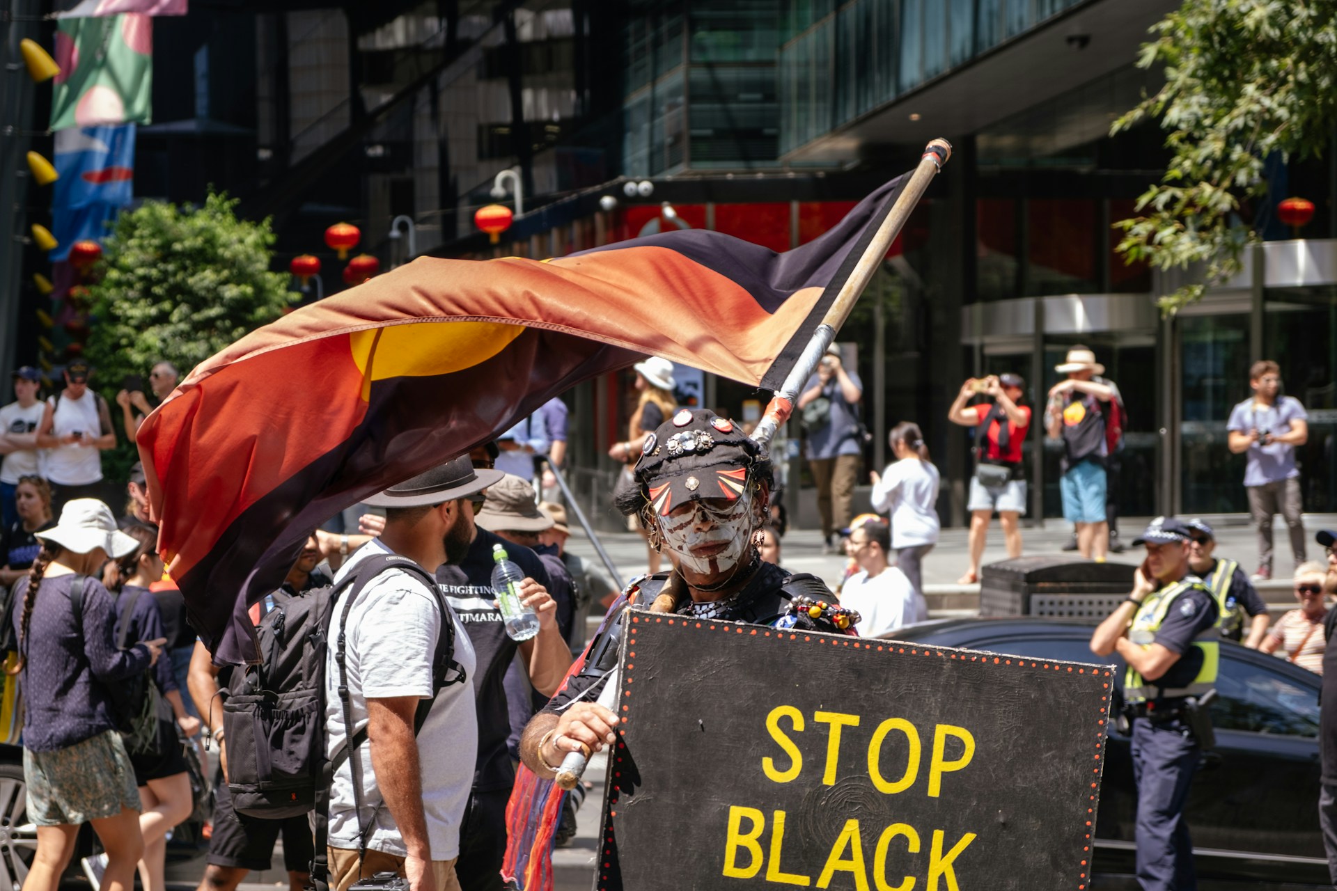 Invasion Day rally, a man holds a sign reading Stop Black Deaths in Custody.