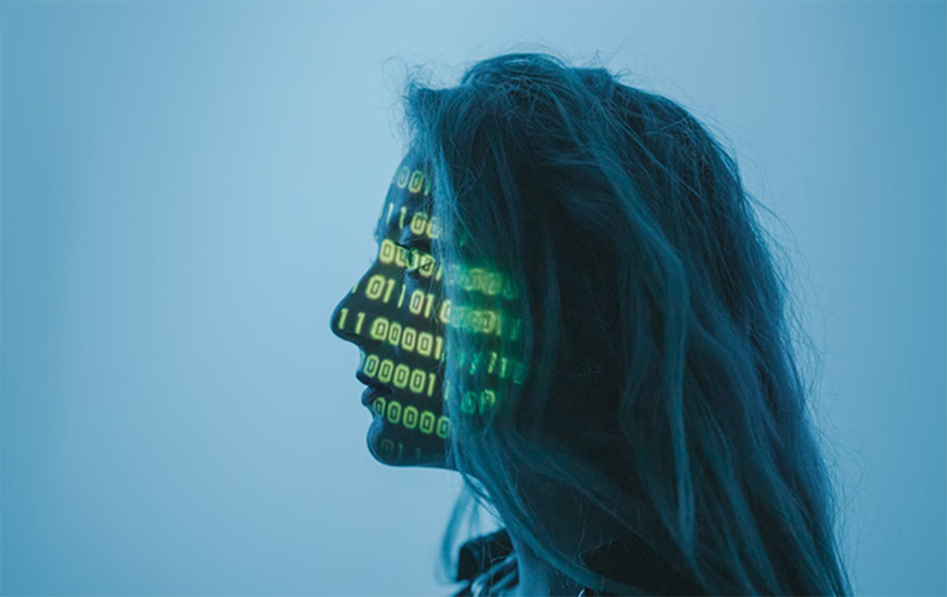 Side profile of a person with long hair with binary code projected on their face