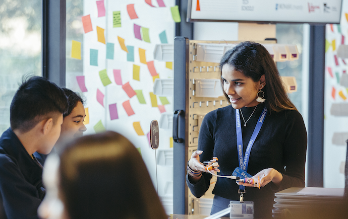 Monash staff teaching high school students in a conference room with whiteboard filled with sticky notes