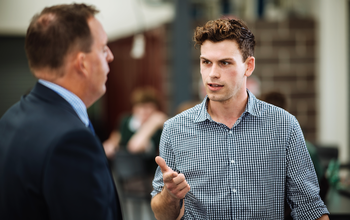 Younger man speaking to senior lecturer
